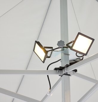 The LED spotlight, consisting of 3 spots, is mounted on the central pole of the folding gazebo. The LED spotlight is on.