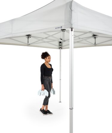 Die Frau trägt die 28 Kg Bodenplatte zum Faltpavillon.