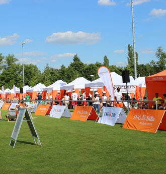 Weißer und orangefarbener 6x3-Faltpavillon mit dekorativen Eckvorhänge und personalisierten ING-DiBa-Fahnen bei einer gesponserten Sportveranstaltung in Deutschland
